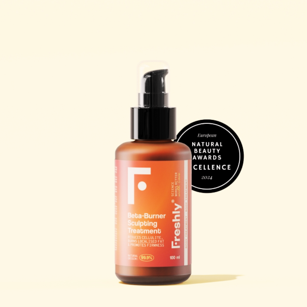 O frasco âmbar com bomba preta rotulado Freshly Creme Anticelulite e Redutor 100ml fica diante de um distintivo preto circular do Natural Beauty Awards Excellence 2024. Ideal para gordura localizada, sobre um fundo claro.