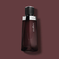 O Boticário Malbec – Eau de Toilette 100 ml – Flasche vor bordeauxrotem Hintergrund